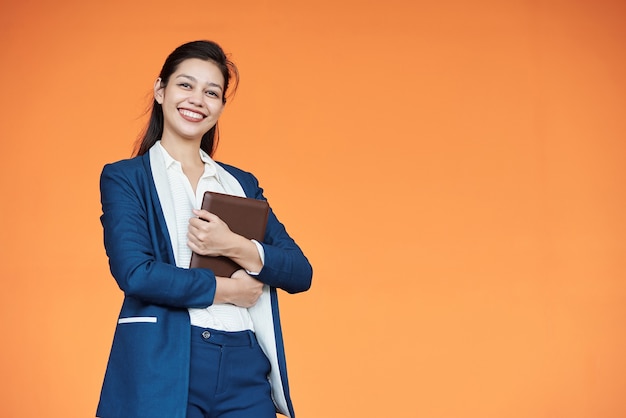 Portret van mooie jonge vrouwelijke ondernemer met tabletcomputer poseren tegen een oranje achtergrond