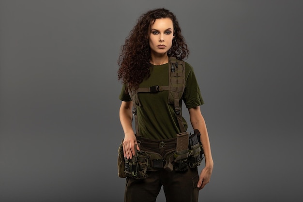 Portret van mooie krullende brunette met serieuze uitdrukking op het gezicht van vrouwelijke soldaat