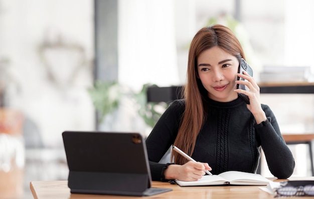 Portret van mooie lachende jonge ondernemer zakenvrouw met behulp van mobiele telefoon en werken in moderne werkplek.