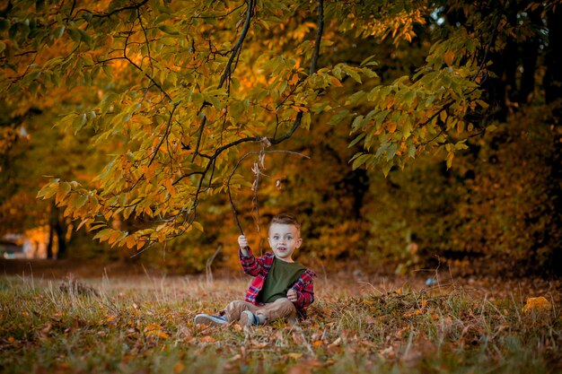 Portret van mooie lachende jongetje in herfst park.