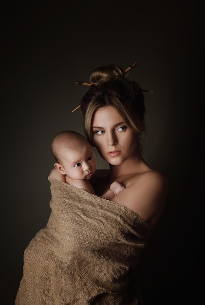 Portret van mooie moeder en haar kleine baby zijn in jute gewikkeld