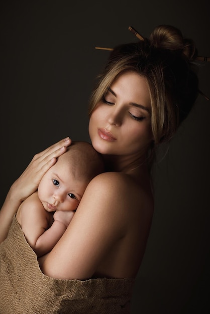 Portret van mooie moeder en haar kleine baby zijn in jute gewikkeld