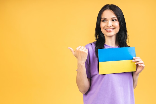 Portret van mooie mooie mooie blije vrolijke vrouw die in handen Oekraïense vlag houdt die pret heeft geïsoleerd over gele pastelkleurachtergrond Wijzende vinger