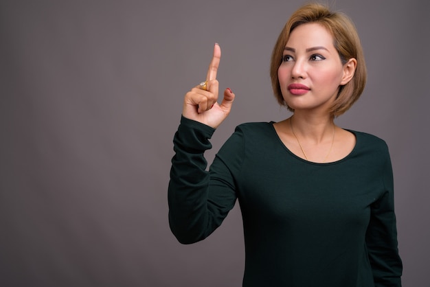 Portret van mooie onderneemster tegen grijze muur