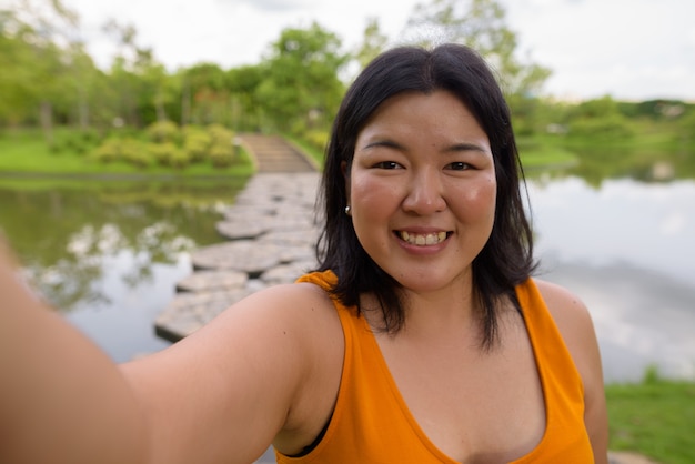 Portret van mooie overgewicht Aziatische vrouw ontspannen in het park in de stad Bangkok, Thailand