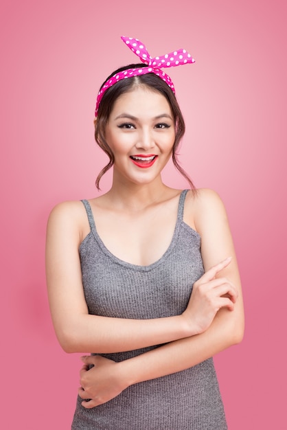 Portret van mooie pinup Aziatische vrouw met vintage make-up en kapsel. Geïsoleerd op roze achtergrond