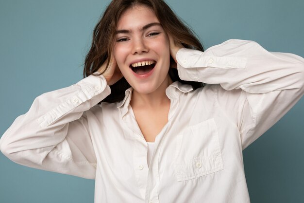 Portret van mooie positieve vrolijke schattige lachende jonge brunette vrouw in casual wit overhemd