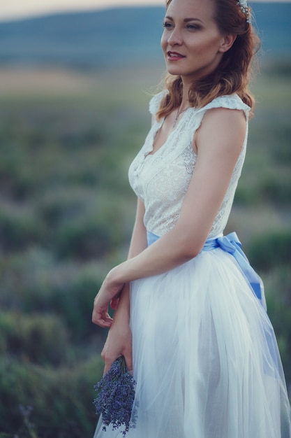 Portret van mooie romantische vrouw in fee gebied van lavendel met boeket