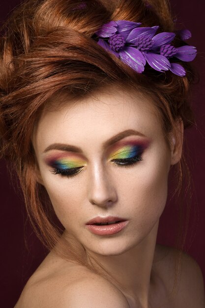 Portret van mooie roodharige vrouw met kleurrijke creatieve make-up naar beneden te kijken