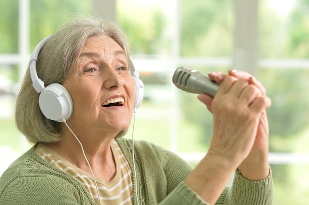 Portret van mooie senior vrouw zingen met microfoon