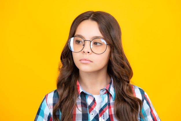 Portret van mooie serieuze tienermeisje op gele studio achtergrond