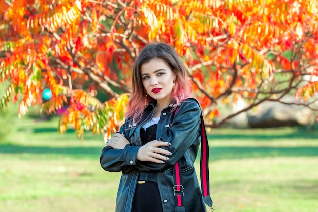Portret van mooie stijlvolle jonge vrouw voor heldere kleurrijke herfst bladeren