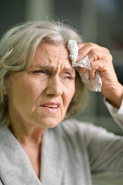 Portret van mooie trieste senior vrouw met hoofdpijn