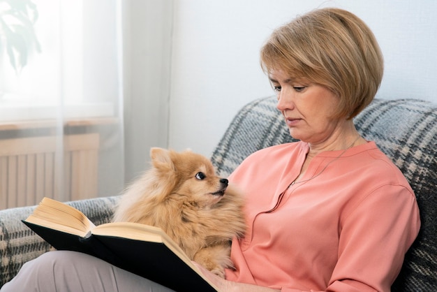 Portret van mooie volwassen senior vrouw is ontspannen lezen interessant boek thuis zittend op