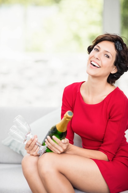 Portret van mooie vrouw die en champagnefles en glas glimlacht houdt