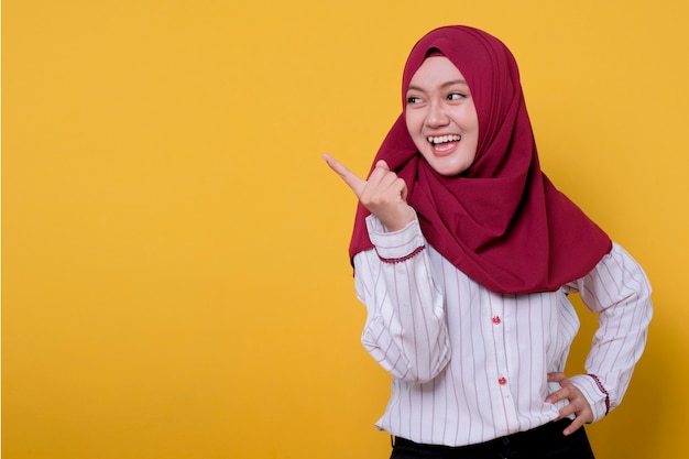 Portret van mooie vrouw die hijab draagt die naar rechts wijst, glimlachend en uitdrukking opvrolijkt