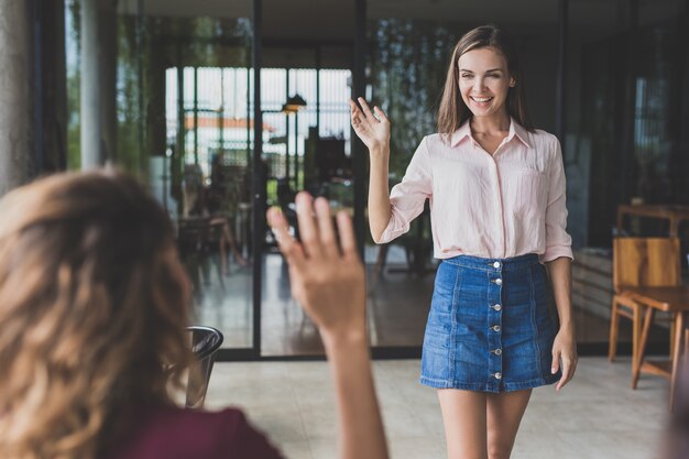 Portret van mooie vrouw haar handen zwaaien naar haar vrienden tijdens het wandelen in hen