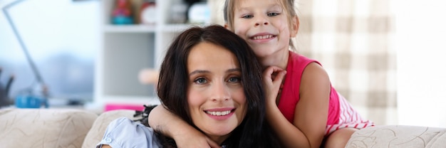 Portret van mooie vrouw het besteden tijd met dochter thuis. Klein kind en vrolijke moeder lacht en kijkt naar de camera met geluk. Moederschap en jeugdconcept