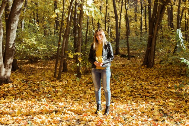 Portret van mooie vrouw houdt herfstbladeren. Stijlvol jeugd- en herfstseizoenconcept.