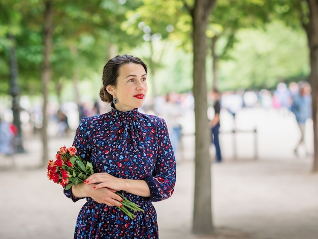 Portret van mooie vrouw in een donkerblauwe jurk genieten van een wandeling in het park