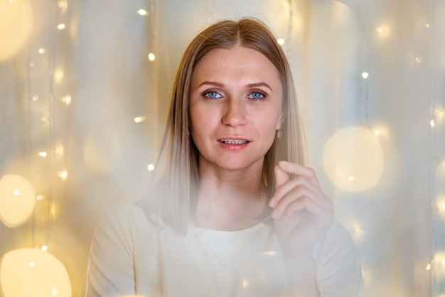 Foto portret van mooie vrouw met blauwe ogen close-up bokeh slingers in delicate toon meisje is celebrati...