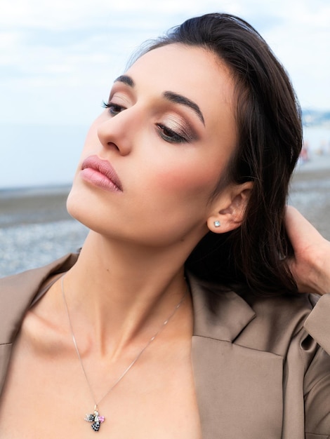 portret van mooie vrouw met donker haar op de achtergrond van de zee Het model kijkt weg