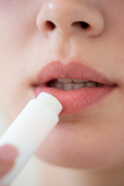 Foto portret van mooie vrouw met heldere huid die lippenbalsem gebruikt