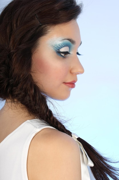 Portret van mooie vrouw met make-up over blauwe achtergrond