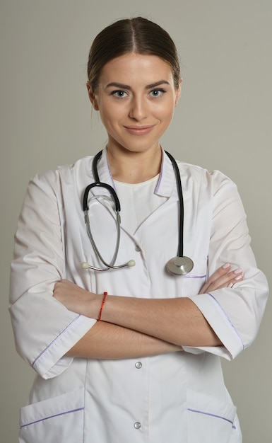 Portret van mooie vrouwelijke arts met stethoscoop, staande ik op grijze achtergrond