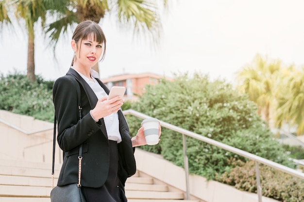Portret van mooie zakenvrouw die smartphone gebruikt op weg naar haar werk
