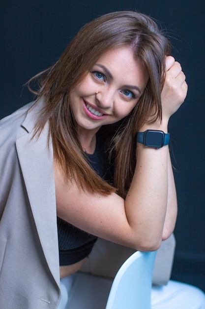 Portret van mooie zakenvrouw in grijs pak en horloge bij de hand. Vrouw met blauwe ogen