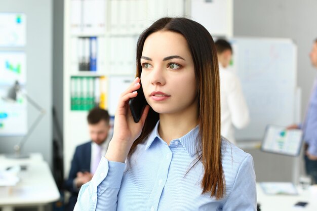 Portret van mooie zakenvrouw met telefoon in kantoor