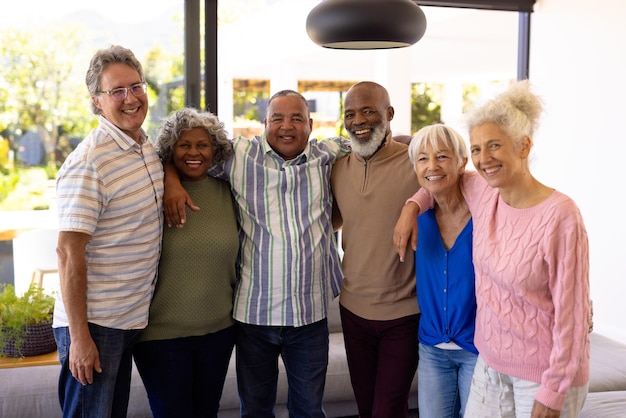 Portret van multiraciale vrolijke senior vrienden met armen om zich heen in verpleeghuis. Gelukkig, ongewijzigd, vriendschap, saamhorigheid, ondersteuning, begeleid wonen en pensioenconcept.
