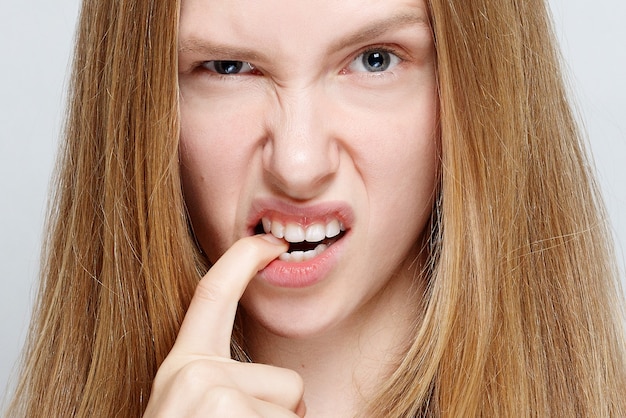 Foto portret van nerveuze mooie jonge vrouw die haar nagels bijt