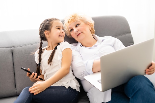 Portret van oma en kleindochter die thuis samen online winkelen.