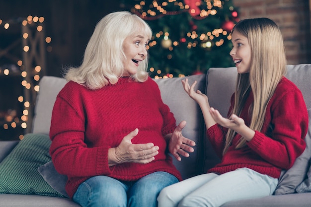 Portret van oma kleinkind zitten op divan grappige verhalen delen in loft huis binnenshuis