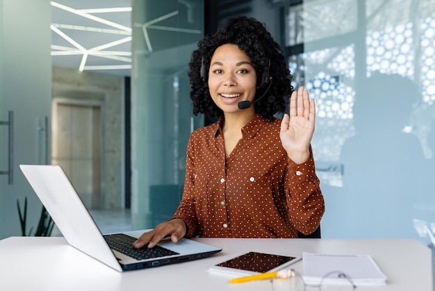 Portret van online klantenservice call center werknemer vrouw glimlachend en kijkend naar camera zwaaien