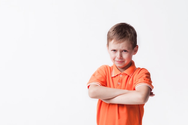 Portret van onschuldige die jongen met wapen tegen witte muur wordt gekruist