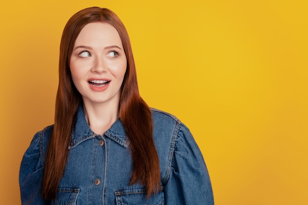 Portret van opgewonden gekke schattige dame kijkt lege ruimte open mond op gele achtergrond