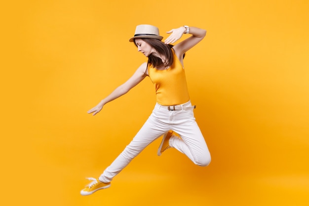 Portret van opgewonden lachende jonge gelukkig springende hoge vrouw in stro zomerhoed, kopieer ruimte geïsoleerd op geeloranje achtergrond. Mensen oprechte emoties, passie levensstijl concept. Reclame gebied.