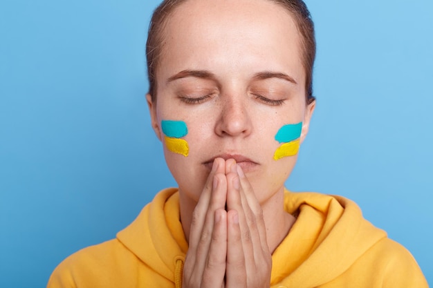 Portret van oren depressief angstige emotionele vrouw met Oekraïne vlag op gezicht bidden voor stop oorlog tussen Rusland en Oekraïne Blijf bij Oekraïne Bid en hoop voor vrede en wereld