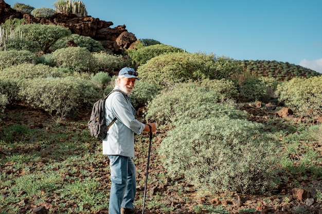 Portret van oude lachende senior man genieten van trekking dag op het platteland Bejaarde man met hoed