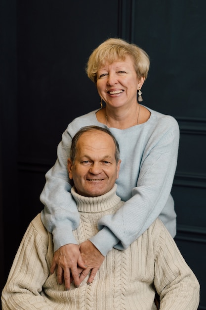 Portret van oude paar vrouw en man knuffelen en glimlachen. Donkerblauwe achtergrond. Gelukkige geliefden op