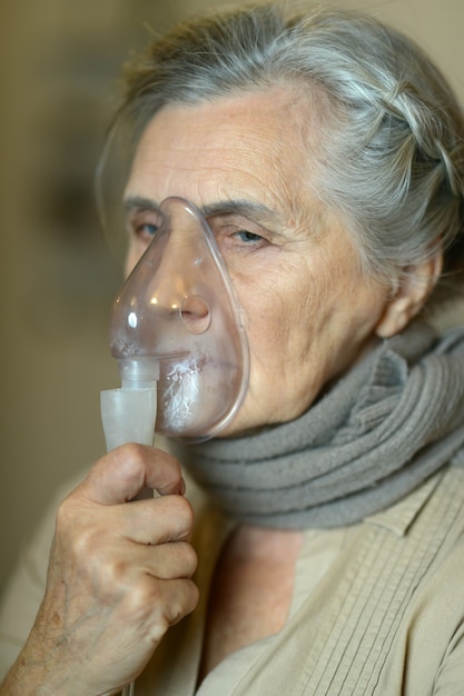 Foto portret van oudere vrouw met griepinhalatie