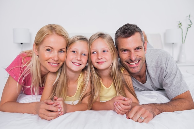 Portret van ouders die in bed met hun kinderen liggen