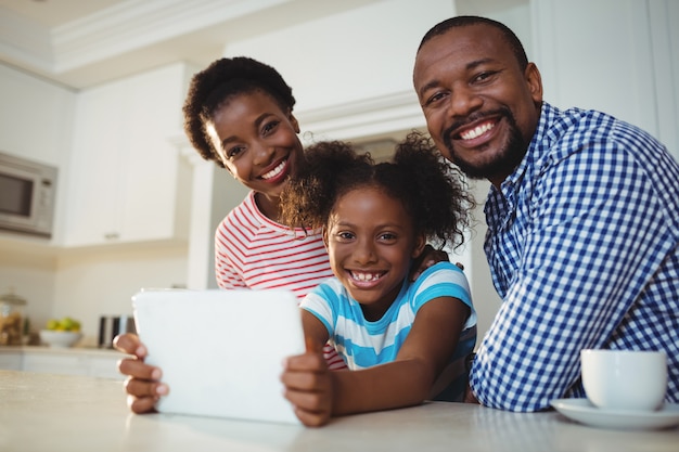 Portret van ouders en dochter die digitale tablet in keuken gebruiken