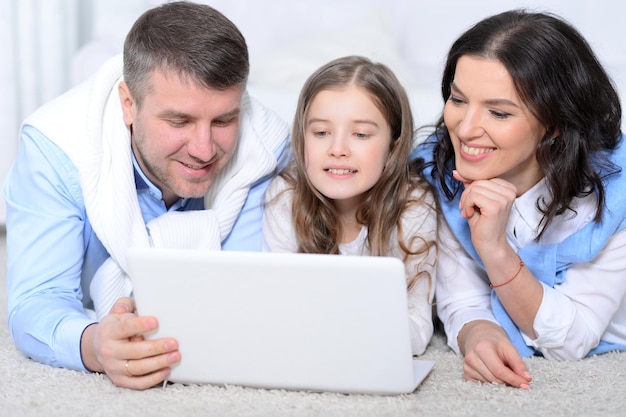 Portret van ouders en dochter die laptop op de kamer gebruiken