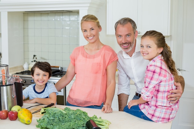 Portret van ouders en hun twee kinderen staan in de keuken