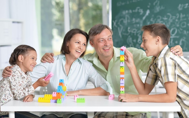 Portret van ouders en kinderen die spelen met kleurrijke plastic blokken in de klas