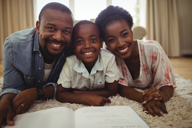 Portret van ouders en zoon die een boek lezen terwijl het liggen op een deken